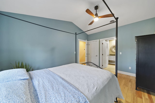 bedroom with ceiling fan, baseboards, vaulted ceiling, light wood-style floors, and ensuite bath