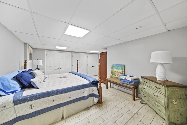 bedroom with light wood-style flooring and a paneled ceiling