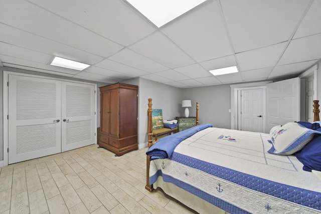 bedroom featuring light wood-style flooring, a paneled ceiling, and a closet