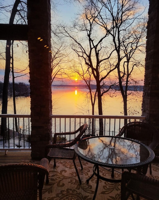 deck at dusk featuring outdoor dining area and a water view