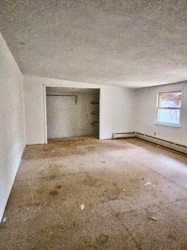 unfurnished bedroom featuring a textured ceiling, baseboard heating, and a closet