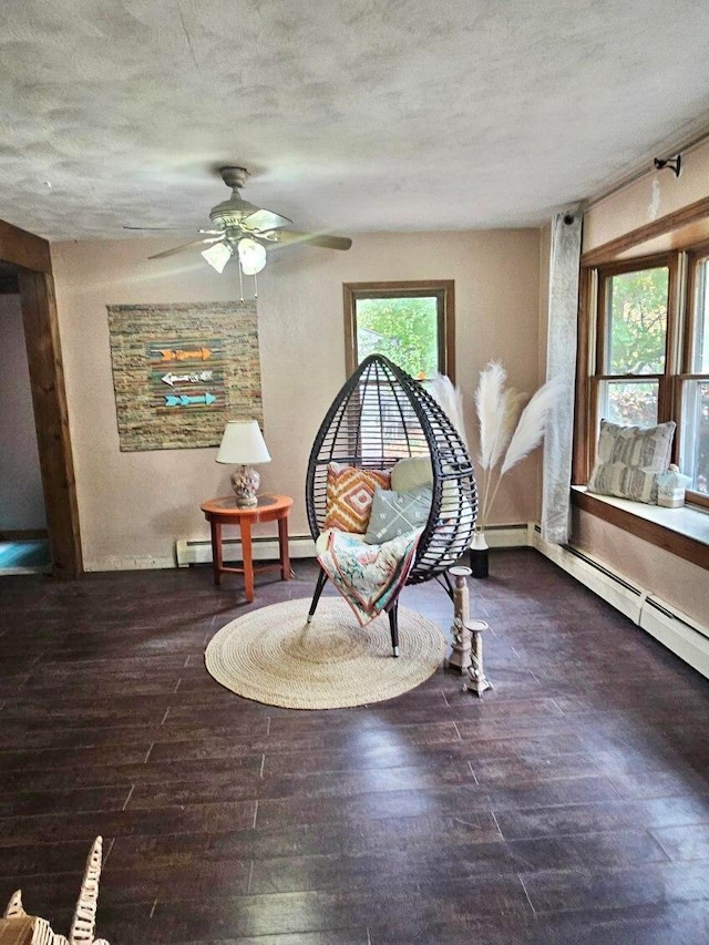 sitting room with dark hardwood / wood-style flooring, baseboard heating, and ceiling fan