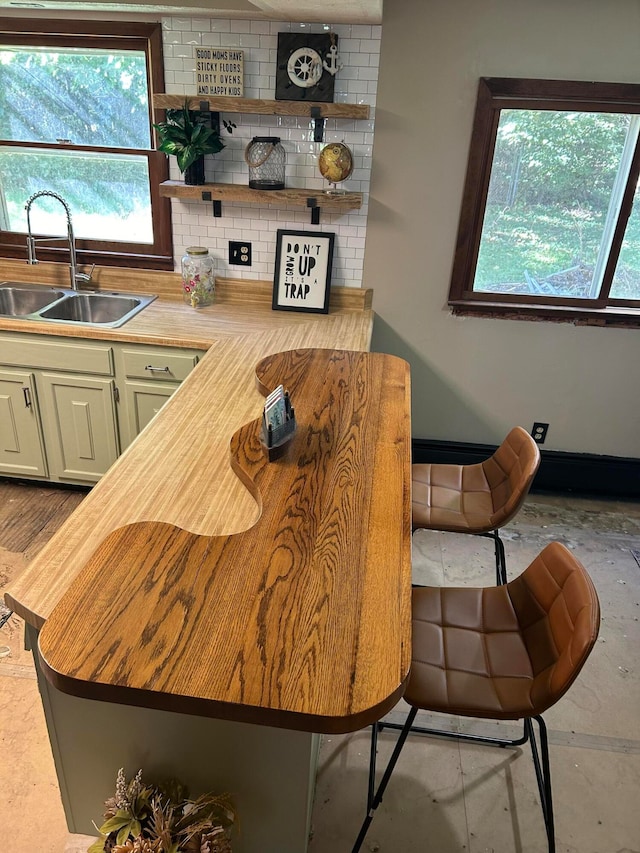 kitchen with a breakfast bar, decorative backsplash, sink, and wooden counters