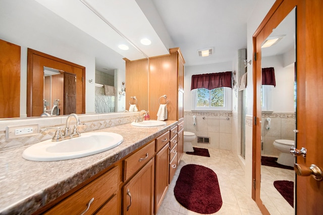 bathroom featuring walk in shower, tile patterned floors, toilet, vanity, and tile walls