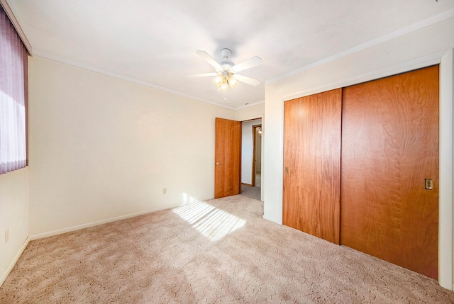 unfurnished bedroom with light carpet, a closet, crown molding, and ceiling fan