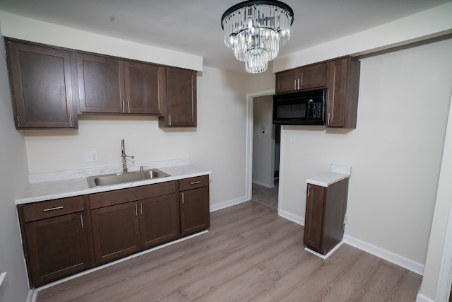 kitchen featuring dark brown cabinetry, sink, and light hardwood / wood-style flooring