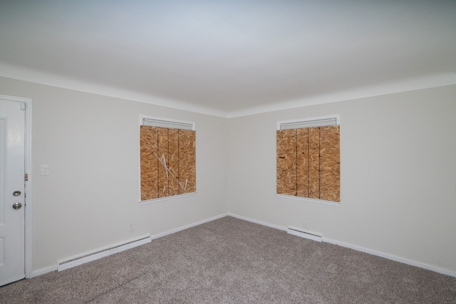 carpeted spare room with a baseboard heating unit