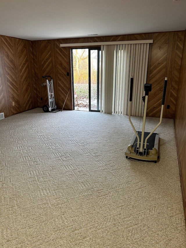 carpeted spare room with wood walls