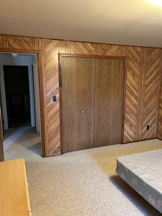 bedroom featuring carpet flooring, wood walls, and a closet