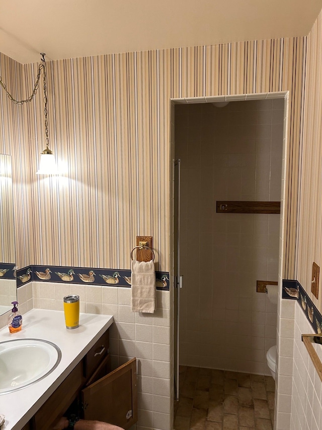 bathroom with vanity, toilet, and tile walls