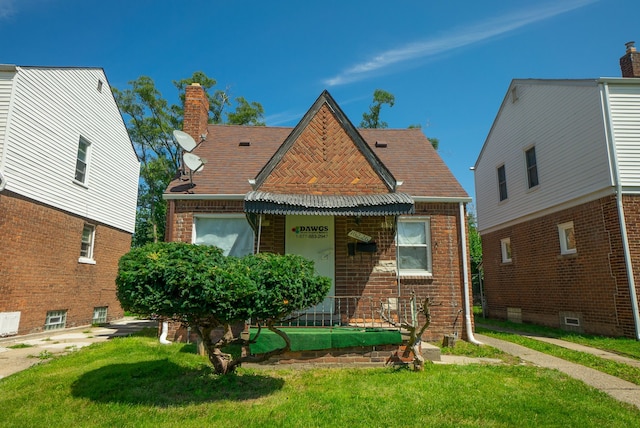 16226 Mark Twain St, Detroit, MI 48235 - tudor home featuring a front yard, brick siding, and a chimney
