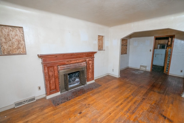 unfurnished living room with a brick fireplace and hardwood / wood-style flooring