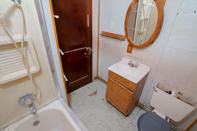 full bathroom featuring vanity, toilet, tile walls, and bathtub / shower combination