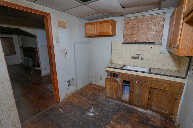 kitchen with decorative backsplash, a drop ceiling, dark wood-type flooring, sink, and tile counters