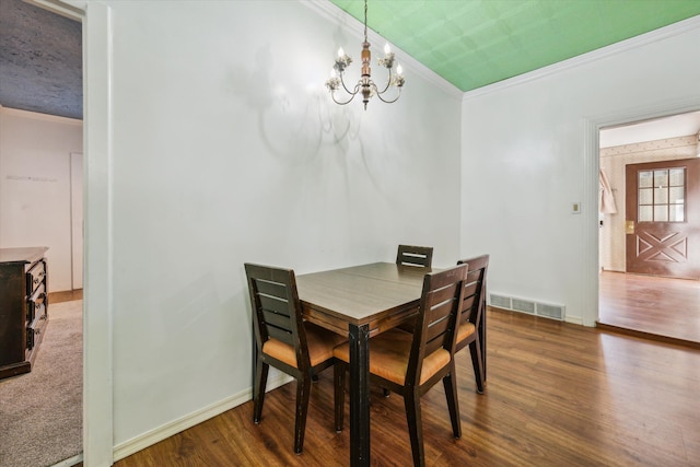 dining area with dark hardwood / wood-style floors, an inviting chandelier, and ornamental molding