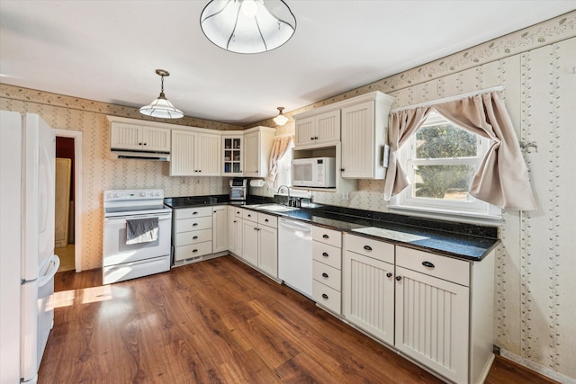 kitchen with pendant lighting, white appliances, dark wood-type flooring, and sink