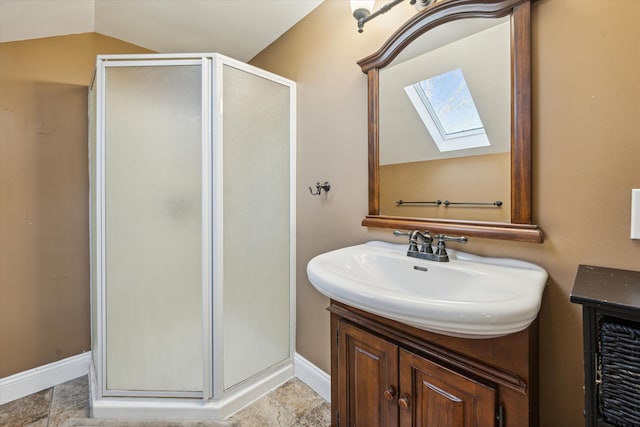 bathroom featuring lofted ceiling with skylight, vanity, and a shower with shower door