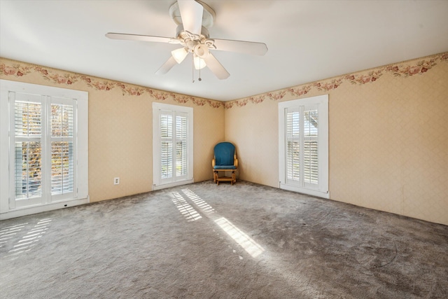 carpeted spare room featuring ceiling fan and a healthy amount of sunlight