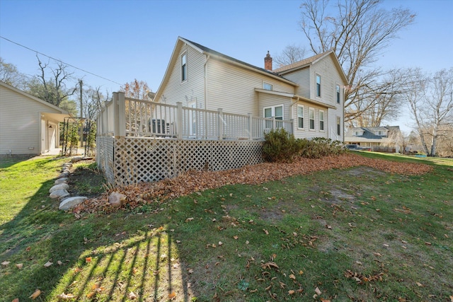 rear view of house with a lawn and a wooden deck