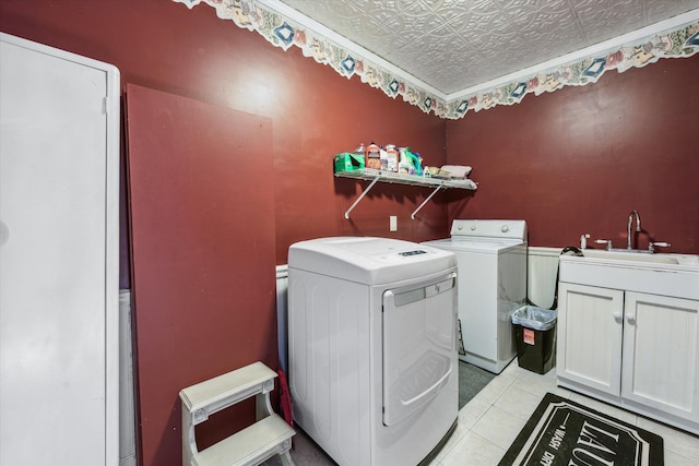 clothes washing area featuring washer and clothes dryer, light tile patterned flooring, cabinets, and sink