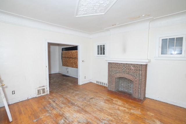 unfurnished living room featuring hardwood / wood-style floors and a brick fireplace