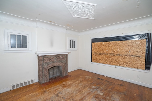 unfurnished living room with wood-type flooring and a brick fireplace