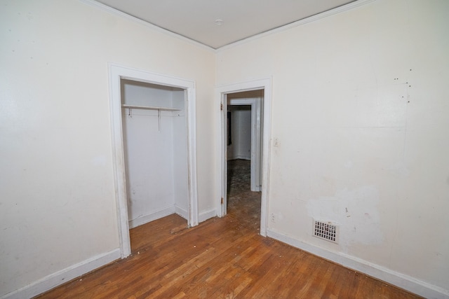 unfurnished bedroom with a closet, hardwood / wood-style floors, and crown molding