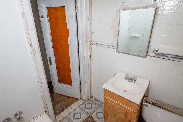 bathroom with vanity, tile walls, and toilet