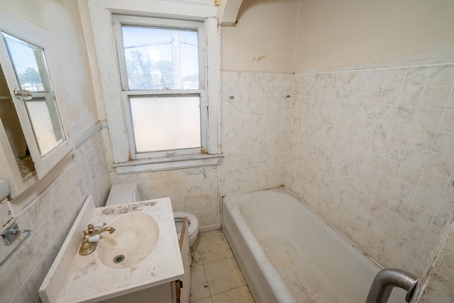 bathroom featuring a washtub, vanity, toilet, and tile walls