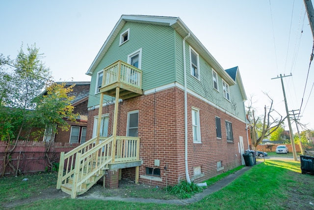 back of house featuring a balcony and a lawn