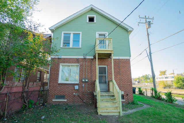 rear view of house featuring a yard and a balcony