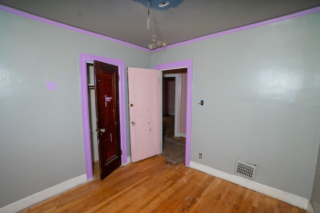 unfurnished bedroom with light wood-type flooring and crown molding