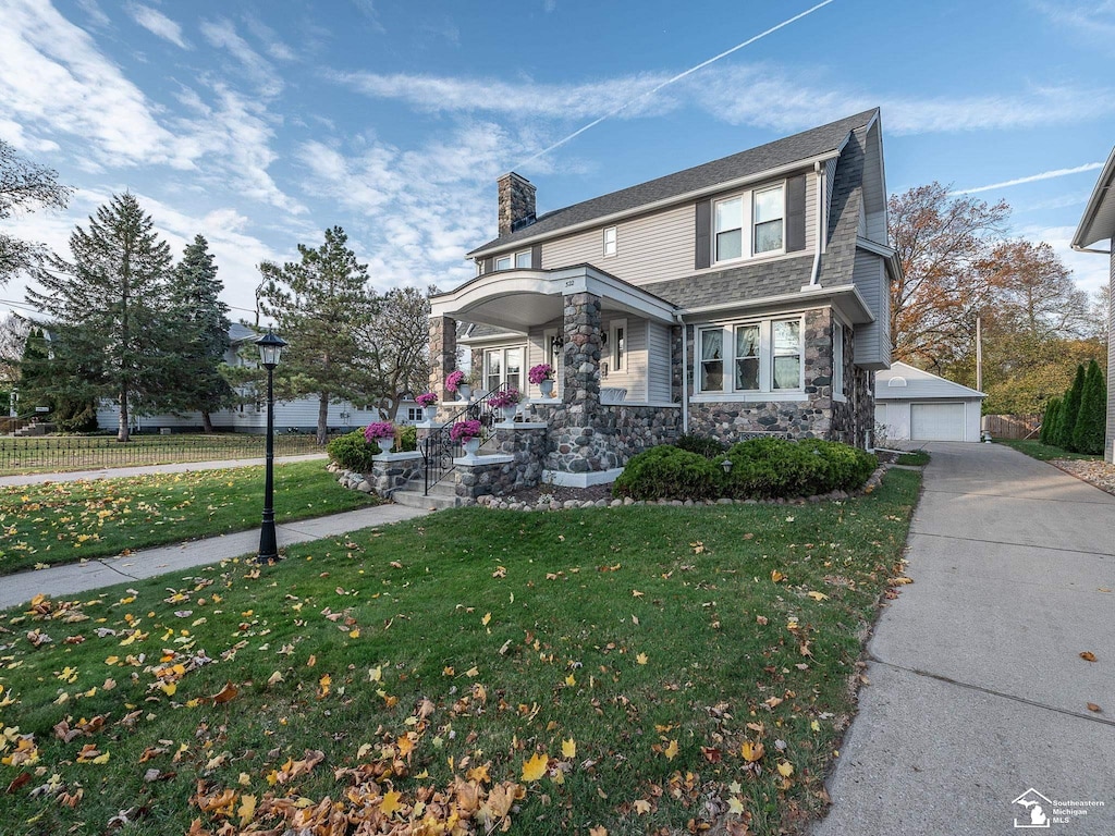 view of property featuring an outdoor structure, a porch, a front yard, and a garage