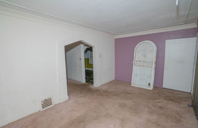 unfurnished room featuring light carpet, a textured ceiling, and ornamental molding