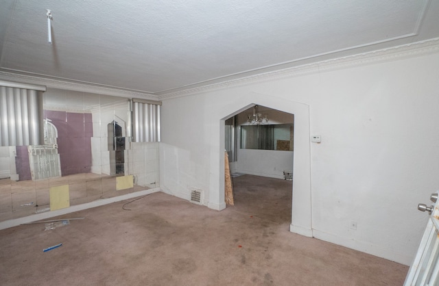 empty room featuring light carpet, crown molding, a textured ceiling, and an inviting chandelier