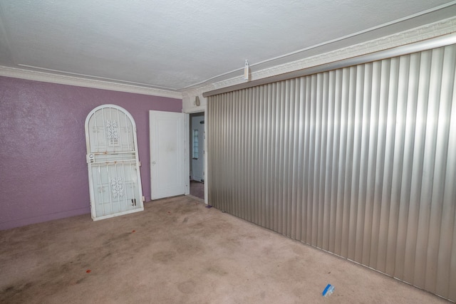 carpeted spare room featuring a textured ceiling and ornamental molding