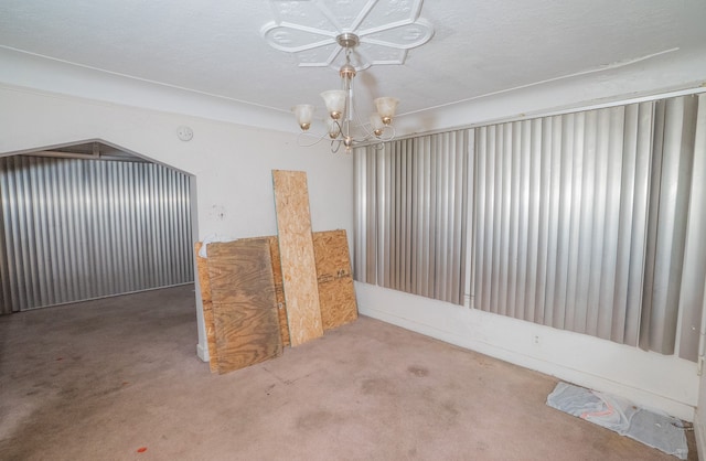 interior space featuring a chandelier, a textured ceiling, and carpet floors