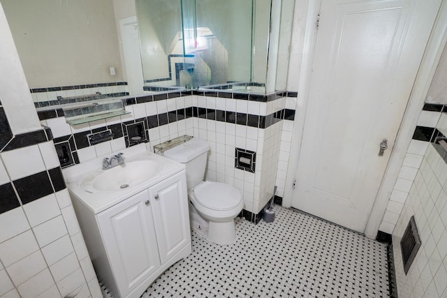 bathroom featuring vanity, tile walls, and toilet