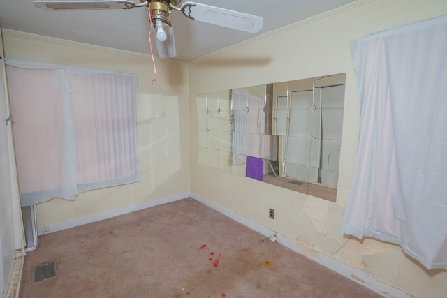 empty room featuring carpet flooring, ceiling fan, and crown molding