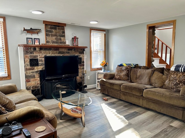 living room featuring stairs, light wood finished floors, visible vents, and baseboards