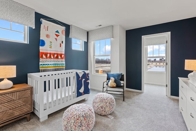 bedroom featuring light carpet, visible vents, baseboards, an accent wall, and a nursery area