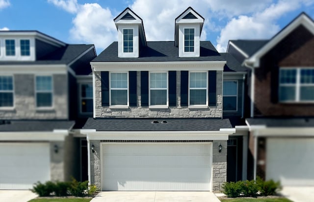 townhome / multi-family property featuring a garage, stone siding, and concrete driveway