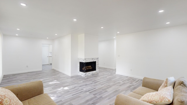 living room featuring a multi sided fireplace and light hardwood / wood-style flooring