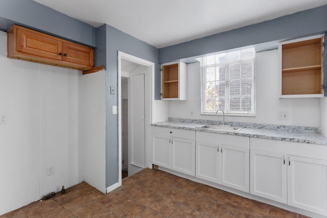 kitchen with light stone counters, sink, and white cabinets