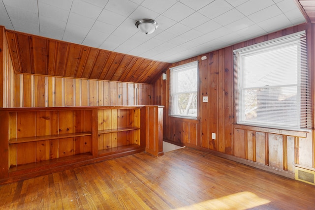 additional living space featuring lofted ceiling, wooden walls, and light hardwood / wood-style flooring