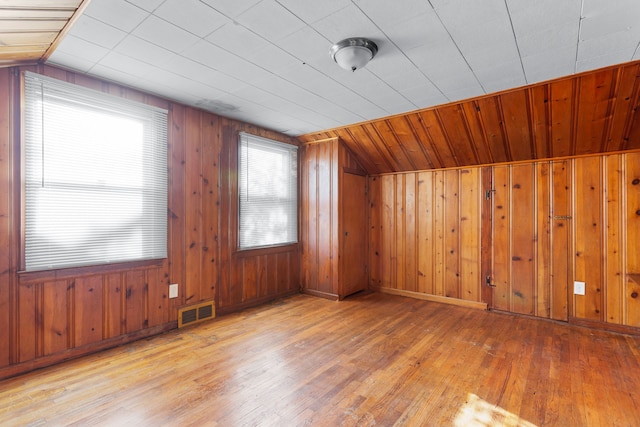 bonus room featuring wood walls, wood-type flooring, and vaulted ceiling