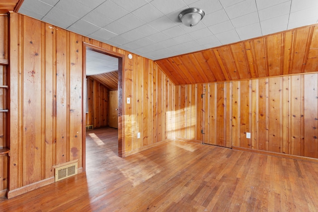 bonus room with wood-type flooring, vaulted ceiling, and wood walls