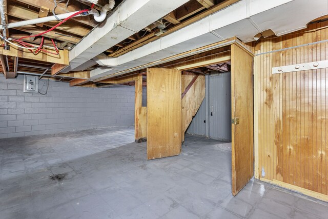 basement featuring electric panel and wood walls