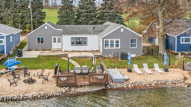 back of property featuring a lawn, cooling unit, and a deck with water view