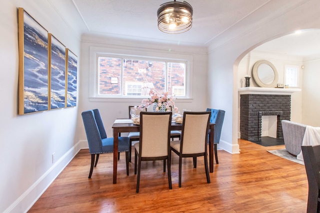 dining room featuring a fireplace, wood-type flooring, and crown molding